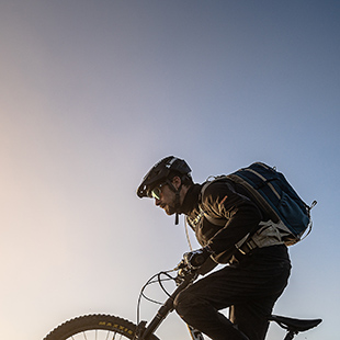 Ein Mann mit Rucksack fährt auf einem Mountainbike.